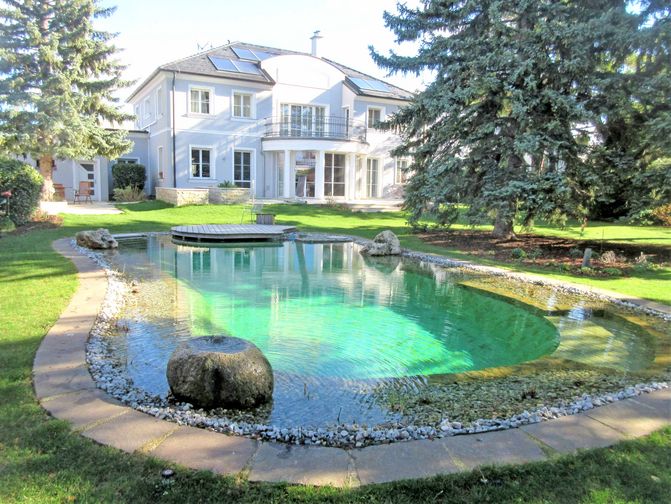 Großer Schwimmteich im Frühling im Garten einer Villa.