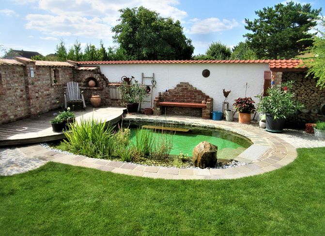 Ein kleiner NANO Teich eingebettet in die Ecke eines Gartens, der vom Nachbar mit einer Mauer getrennt ist.
