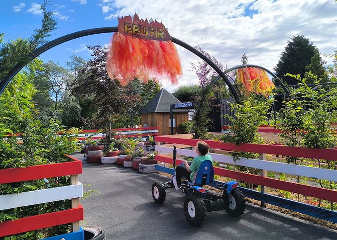 Ein Kind fährt mit einem Gokart auf Europas erster Blumen-Tret-Gokart Bahn durch den "Feuertunnel".