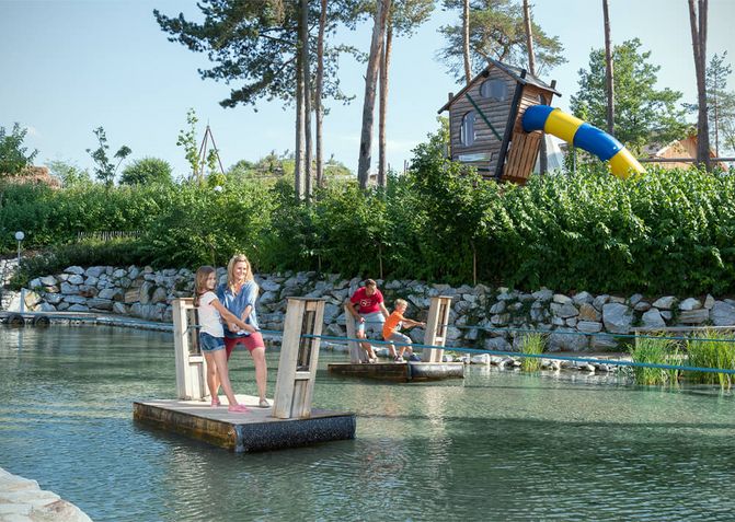 Eine Familie fährt auf dem Floßteich mit zwei Floßen. 