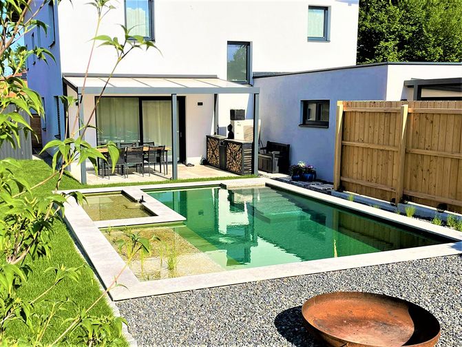 Haus mit Garten und einem quadratischen Naturpool. Vor dem Pool ist eine Kiesfläche mit einer Feuerschale.
