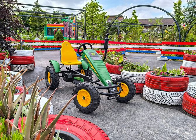 Ein Gokart steht auf der Fahrbahn der Gokartbahn, umgeben von bepflanzten und rot-weiß bemalten Reifen.