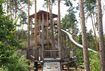 Der Rutschenturm im Abenteuergarten, inmitten von schattenspendenden Bäumen.